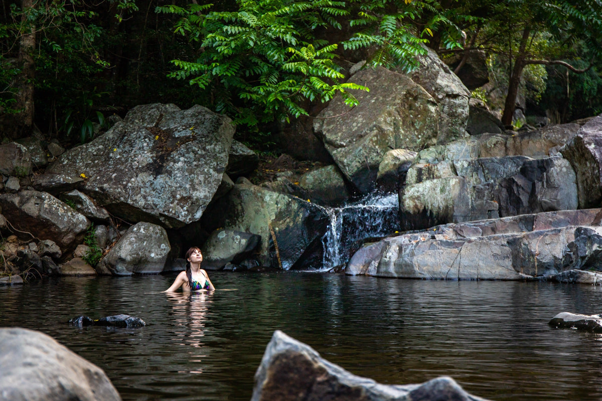 A swimmer in a calm freshwater pool below a small waterfall at Cedar Creek, near Brisbane