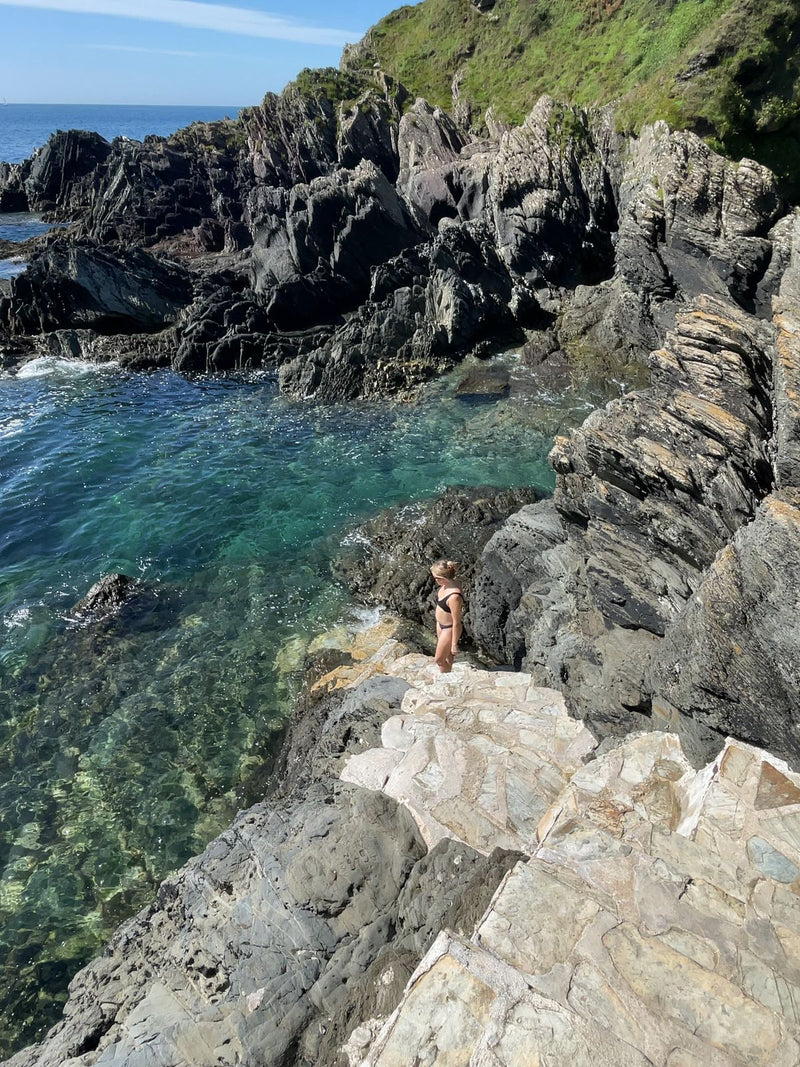 Clear tidal rock pool among rugged cliffs at Chapel Pool, Cornwall, UK