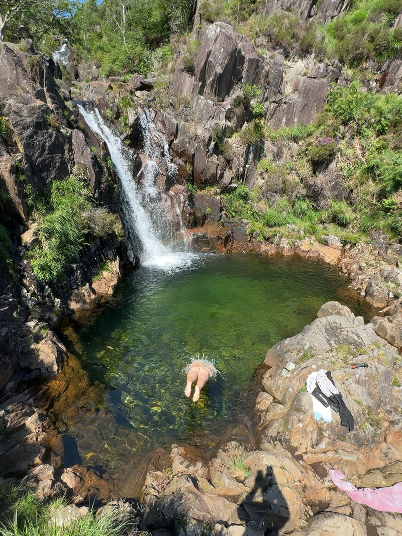 Swimmer in the clear pool below Crawflwyn Beach Waterfall in Wales, UK